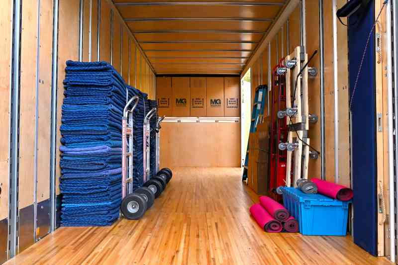packing dolly and tarps strapped to the back cabin of a mg moving services truck